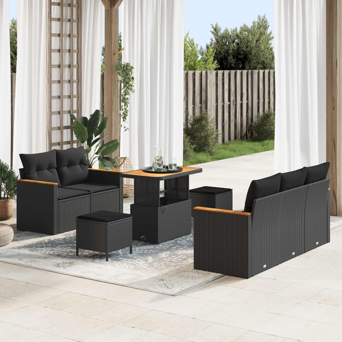 Moderne schwarze Rattan-Gartenmöbel mit Sofa, Tisch und Hockern auf einer Terrasse.