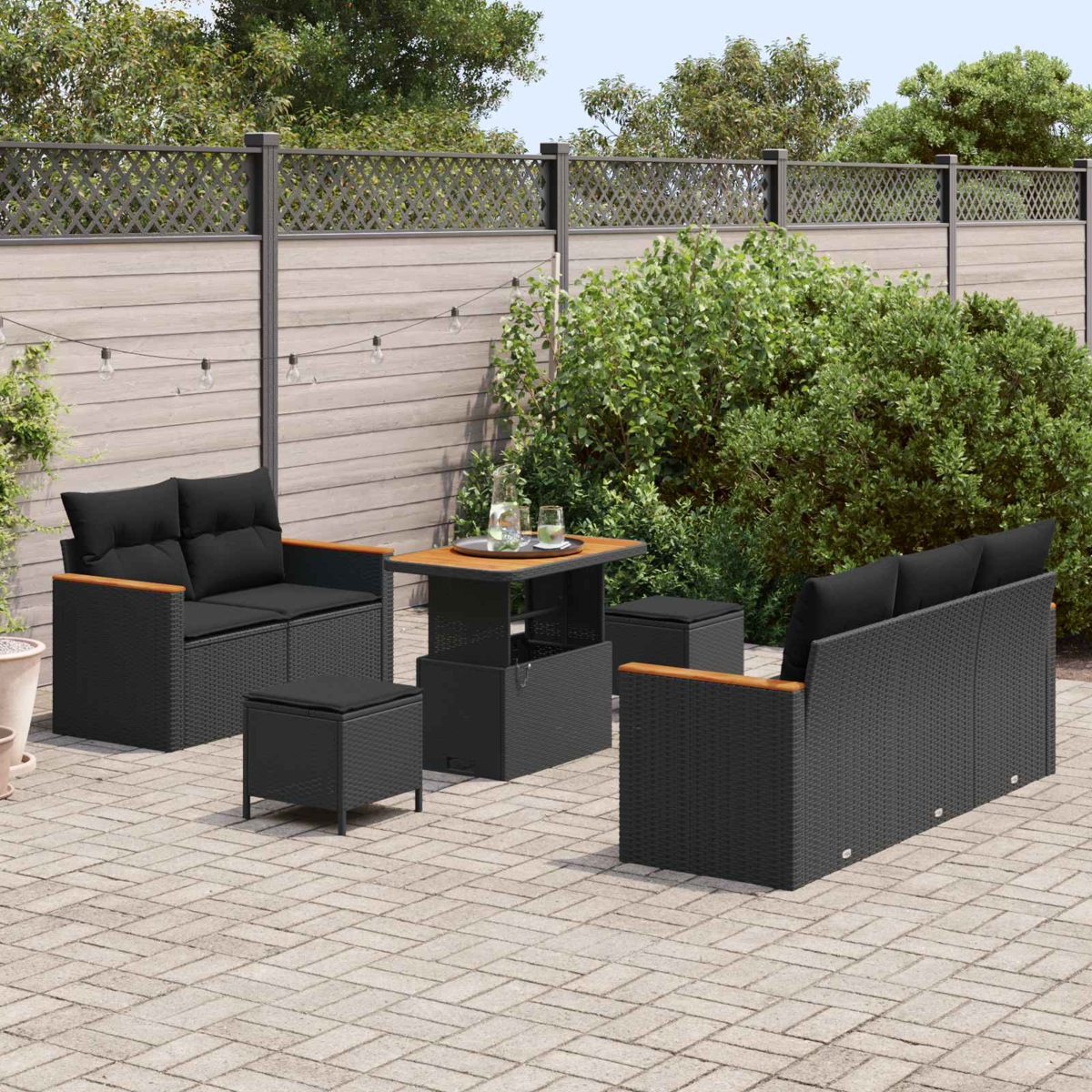 Draußenmöbel-Set mit schwarzen Kissen auf einer Terrasse.