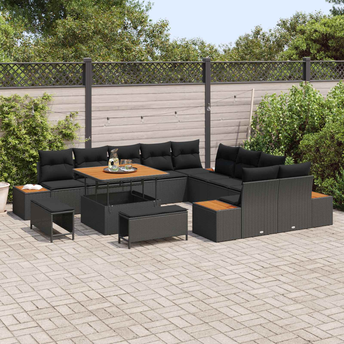 Un set lounge in rattan nero con tavolino da caffè su un patio pavimentato.