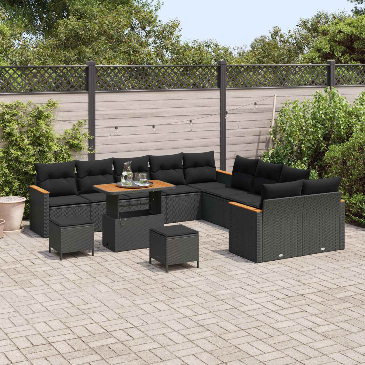 Dunkles Rattan-Ecksofa mit schwarzen Kissen und Holztisch auf gepflastertem Hof.