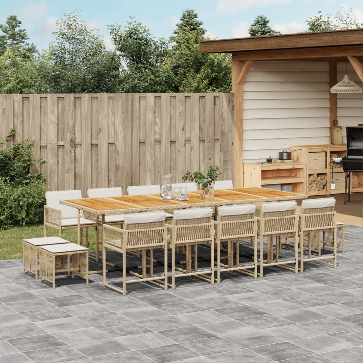 Conjunto de comedor exterior con mesa, sillas y taburetes en un patio embaldosado, cerca de una valla de madera y zona cubierta.
