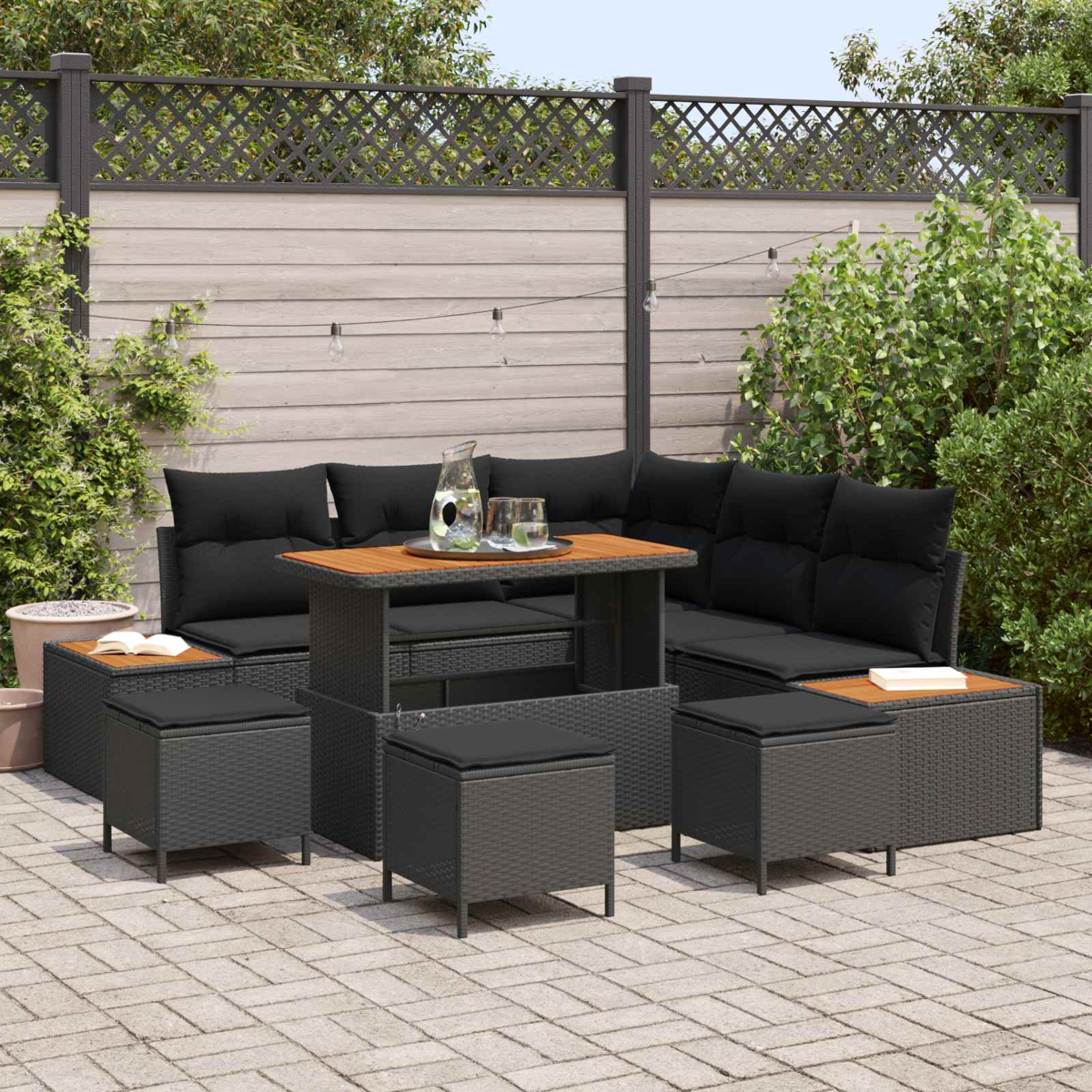 Conjunto de muebles de exterior de ratán gris oscuro, mesa de madera y taburetes en patio.