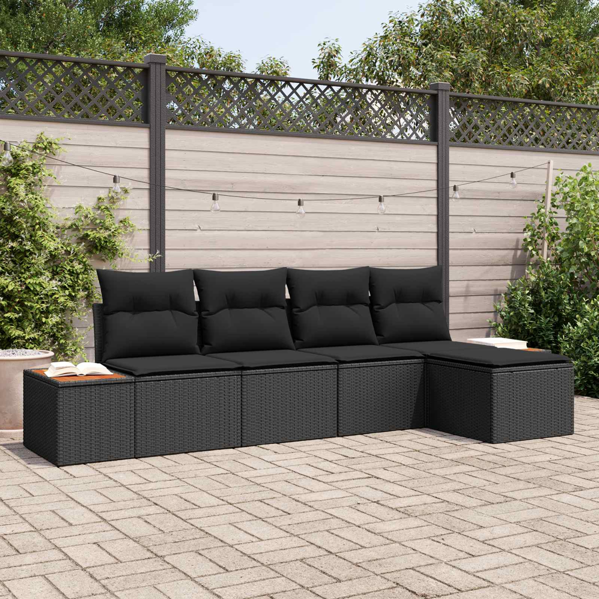 Ein schwarzes modulbares Loungeset mit Kissen auf einer gepflasterten Terrasse.