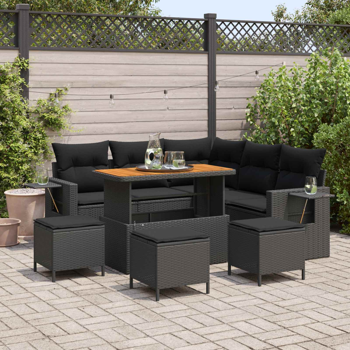 Graue Rattan-Lounge-Möbel mit schwarzen Kissen auf einer Terrasse.