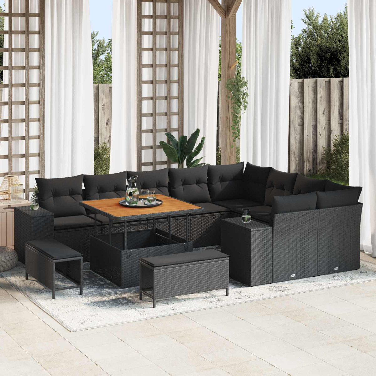 Ein dunkles Rattan-Sofa mit Tisch, Bank und Pflanzen unter einem Baldachin.