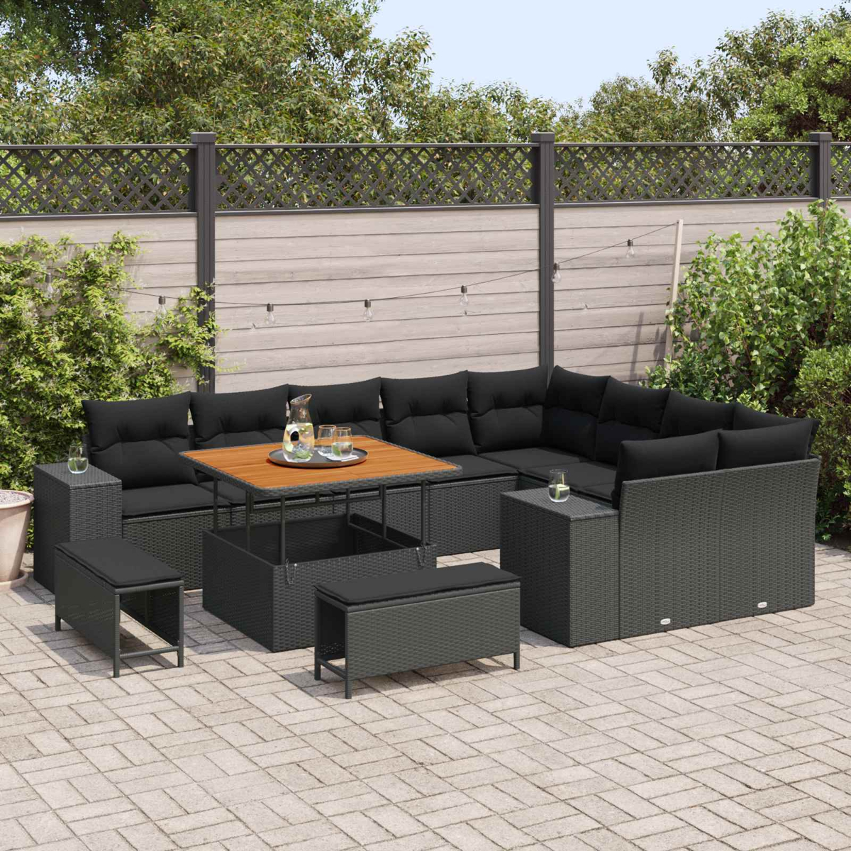Dunkelgraue Rattan-Lounge-Möbel mit schwarzen Kissen und einem Holztisch auf einer Terrasse.
