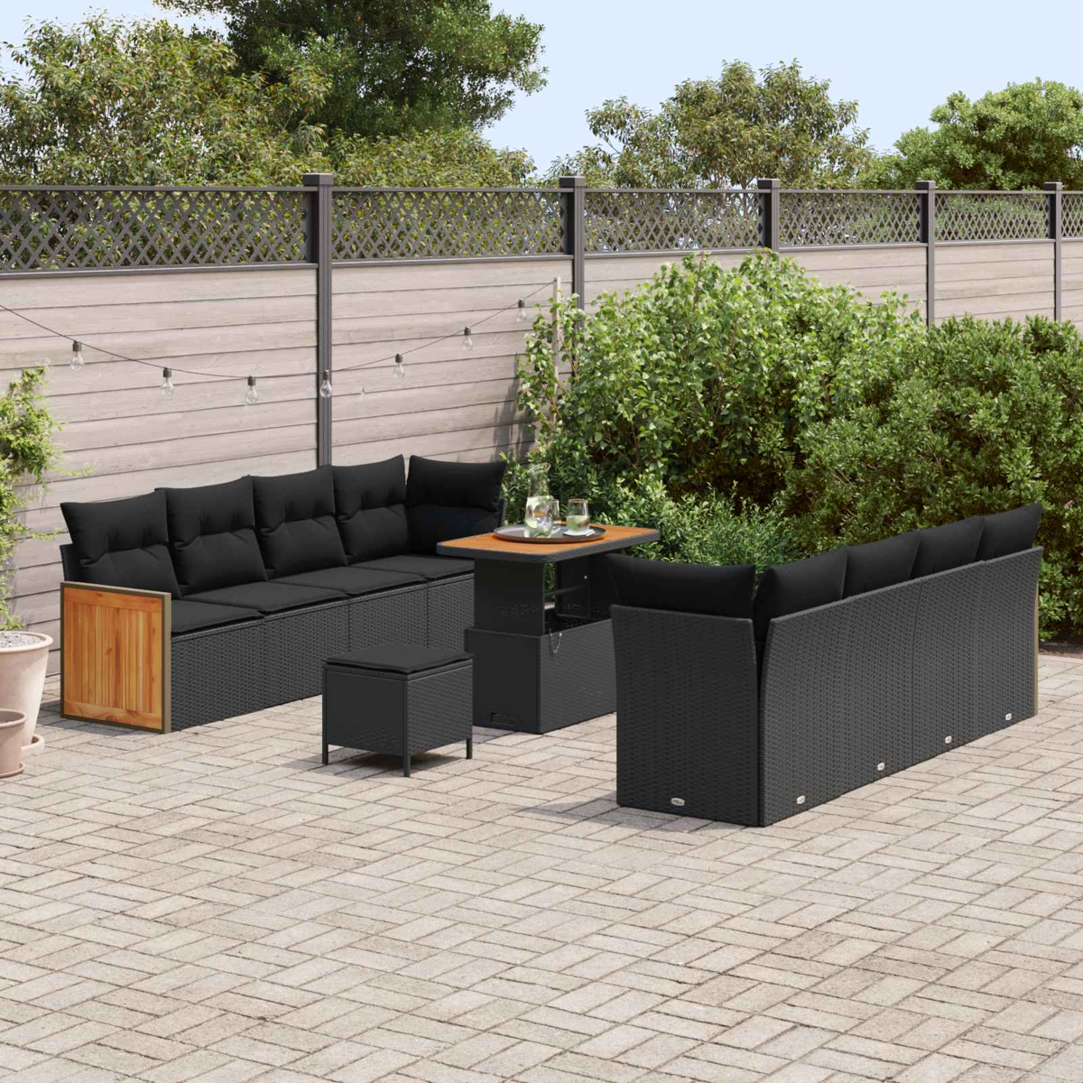 Un divano in rattan nero con cuscini, sgabello e tavolo su un patio.