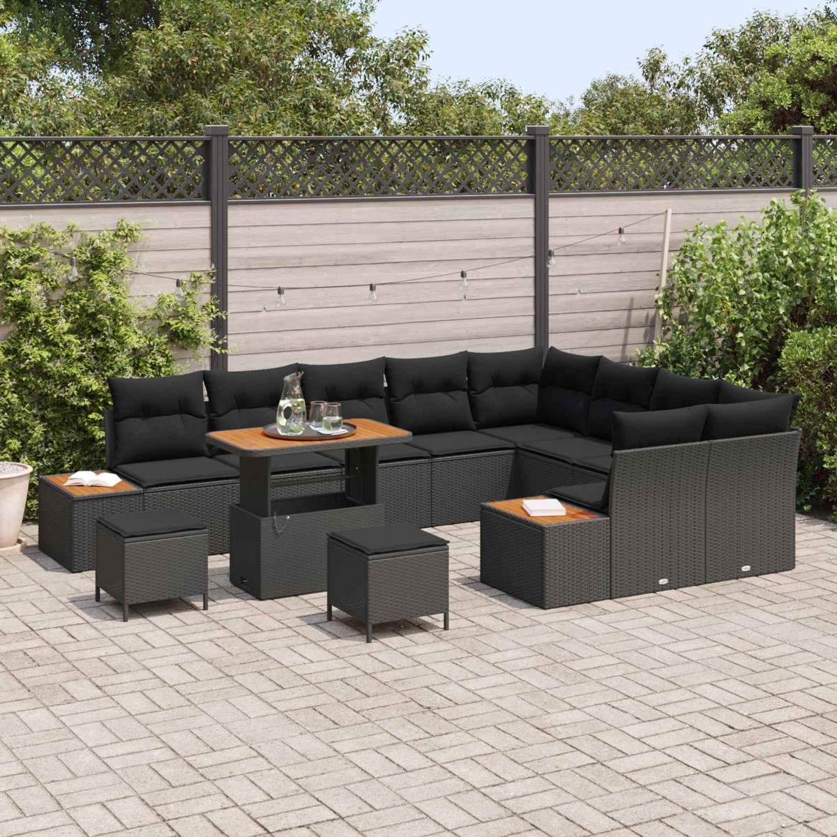 Dunkle Lounge-Möbel mit Kissen und einem Tisch auf einer gepflasterten Terrasse.
