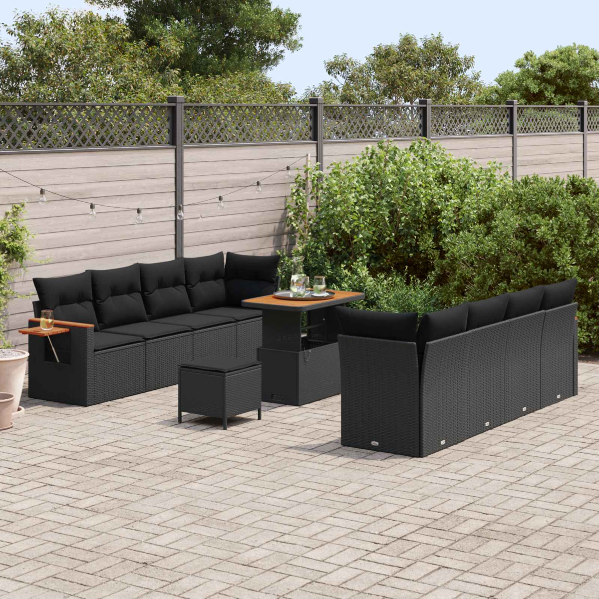 Salotto da esterno in rattan nero con cuscini, tavolo e pouf.