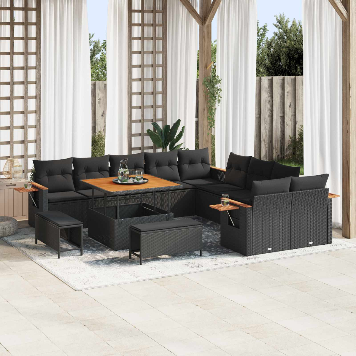 Ein dunkles, modulares Rattansofa mit Kissen und einem Holztisch auf einer Terrasse.