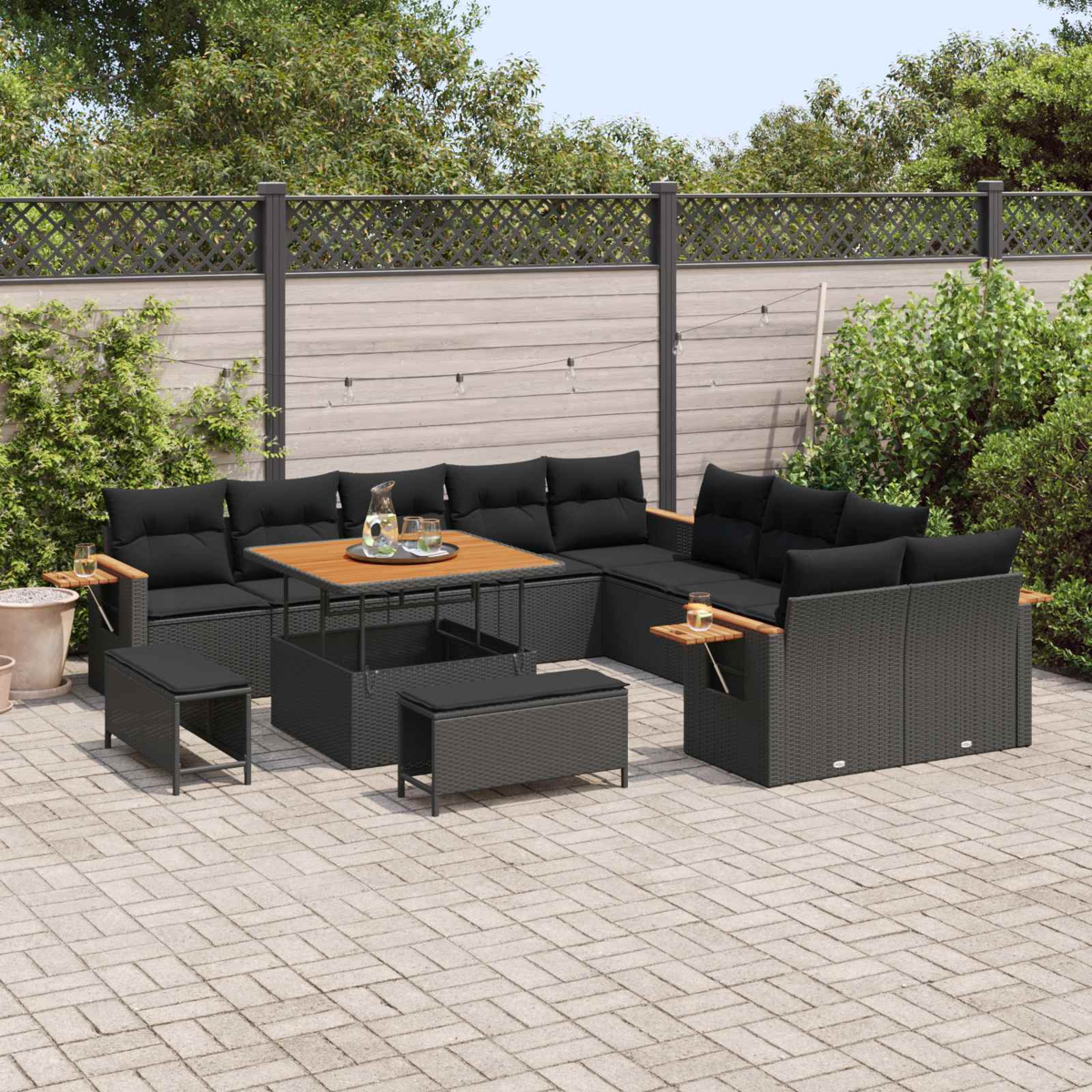 Ein schwarzes Lounge-Set mit Kissen und einem Tisch auf einer gepflasterten Terrasse.