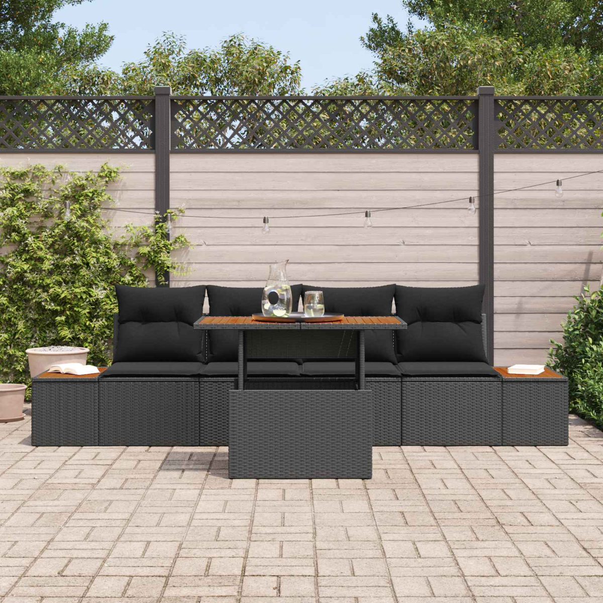 Dunkelgraue Rattan-Lounge mit schwarzen Kissen und Holztisch mit Getränken.