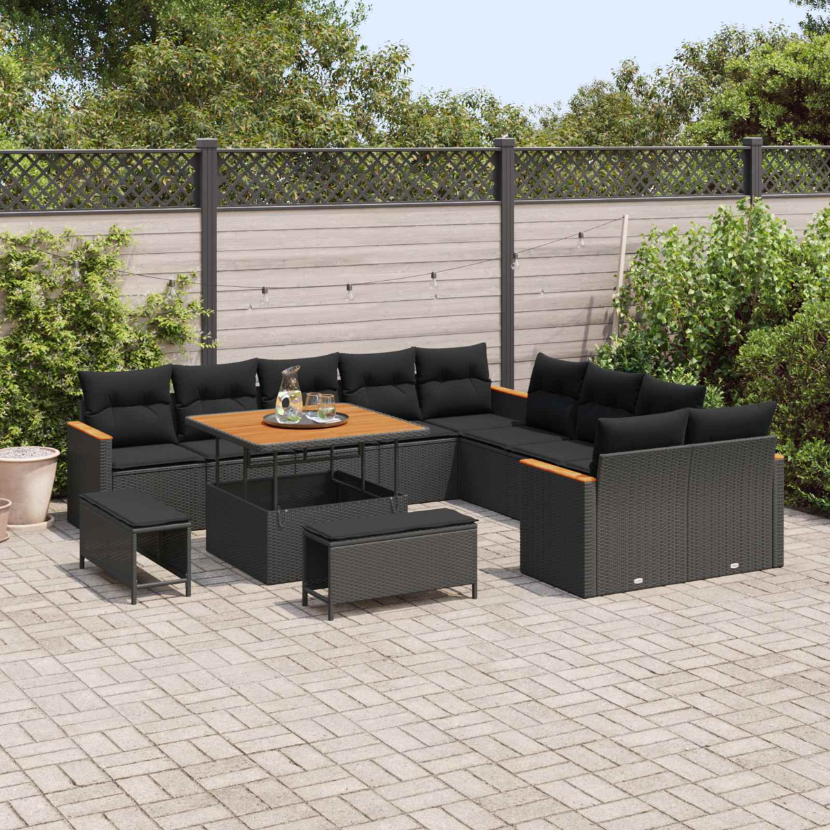 Ein schwarzes Lounge-Set mit Kissen und Tisch auf einer gepflasterten Terrasse.