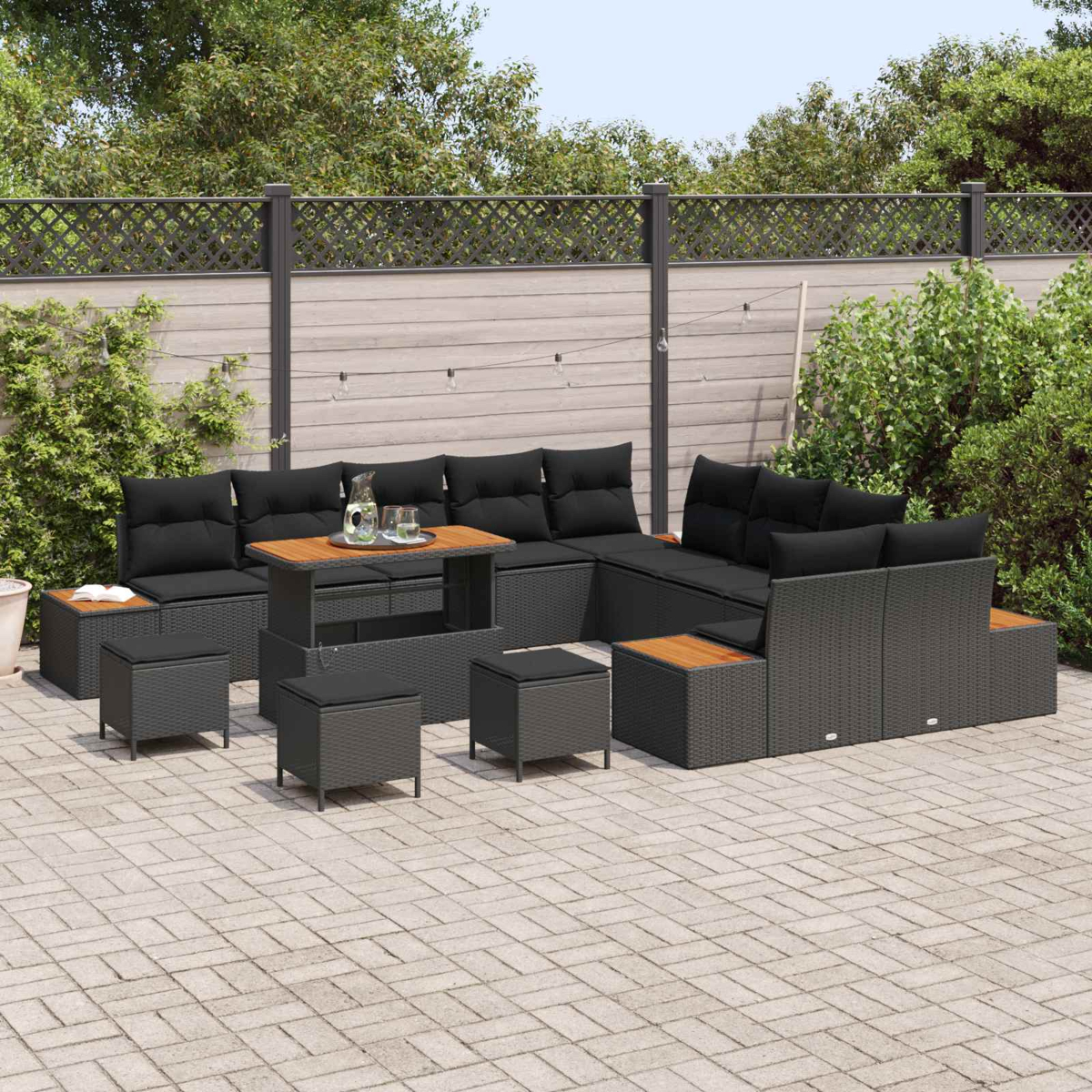 Salotto moderno con cuscini neri e tavolo su un patio pavimentato.