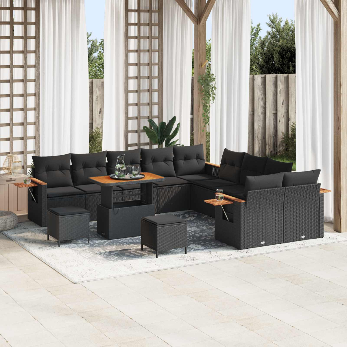 Schwarzes Rattan-Sofa mit Kissen, Couchtisch und Hockern auf einer Terrasse.