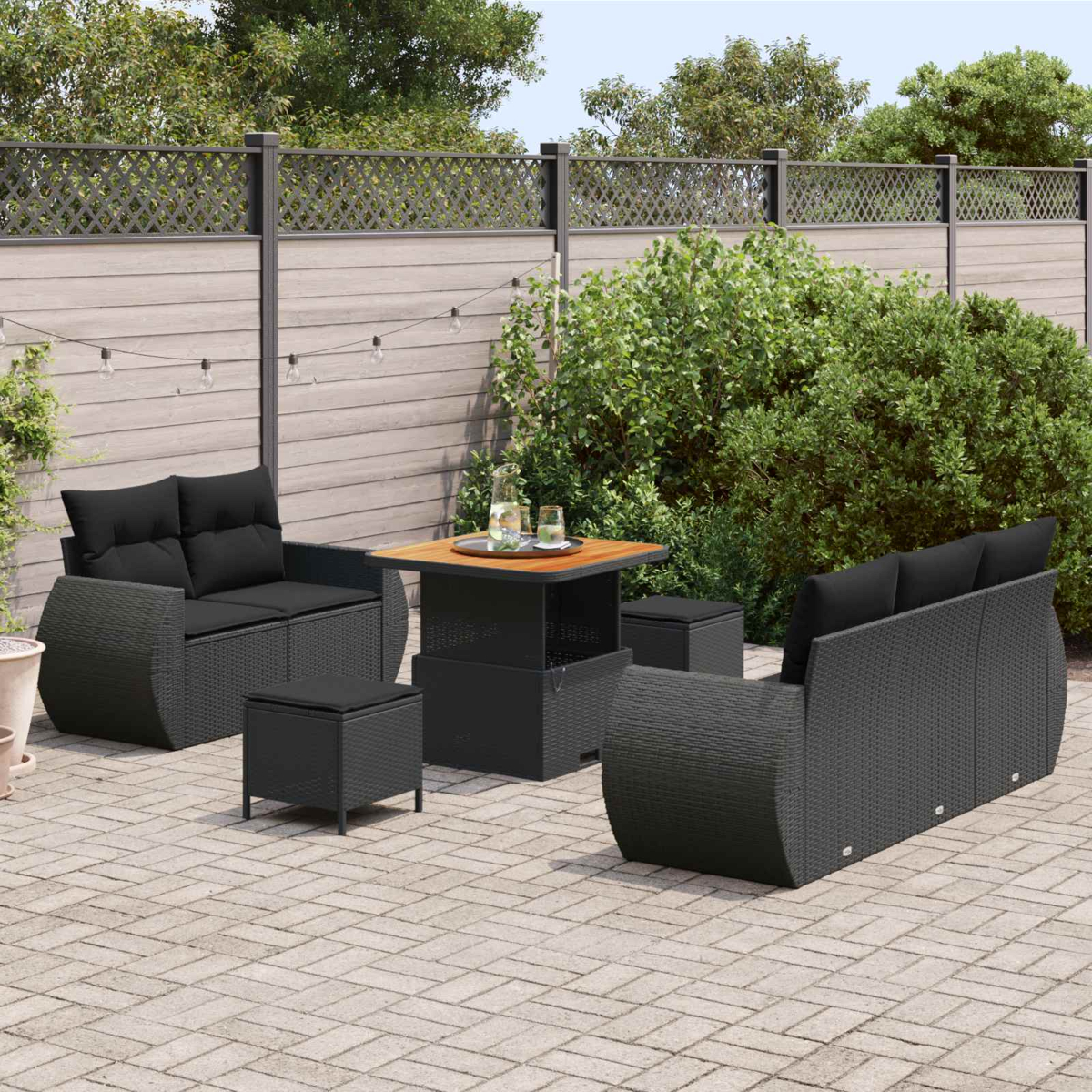 Ein dunkles Polyrattan-Möbelset mit Sofa, Sesseln und Tisch auf einer Terrasse.