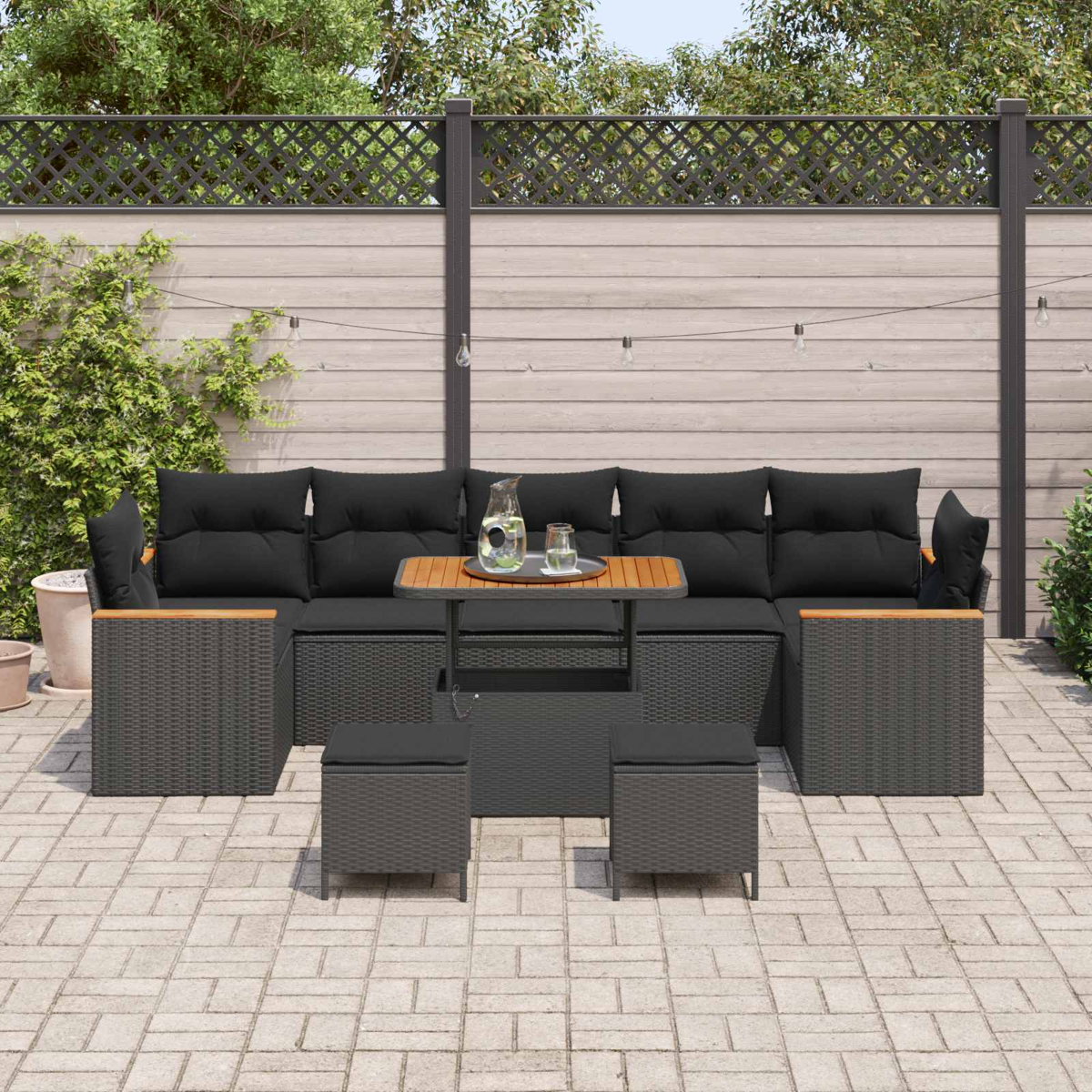 Graue Lounge-Möbel mit schwarzen Kissen und Holztisch auf einer gepflasterten Terrasse.
