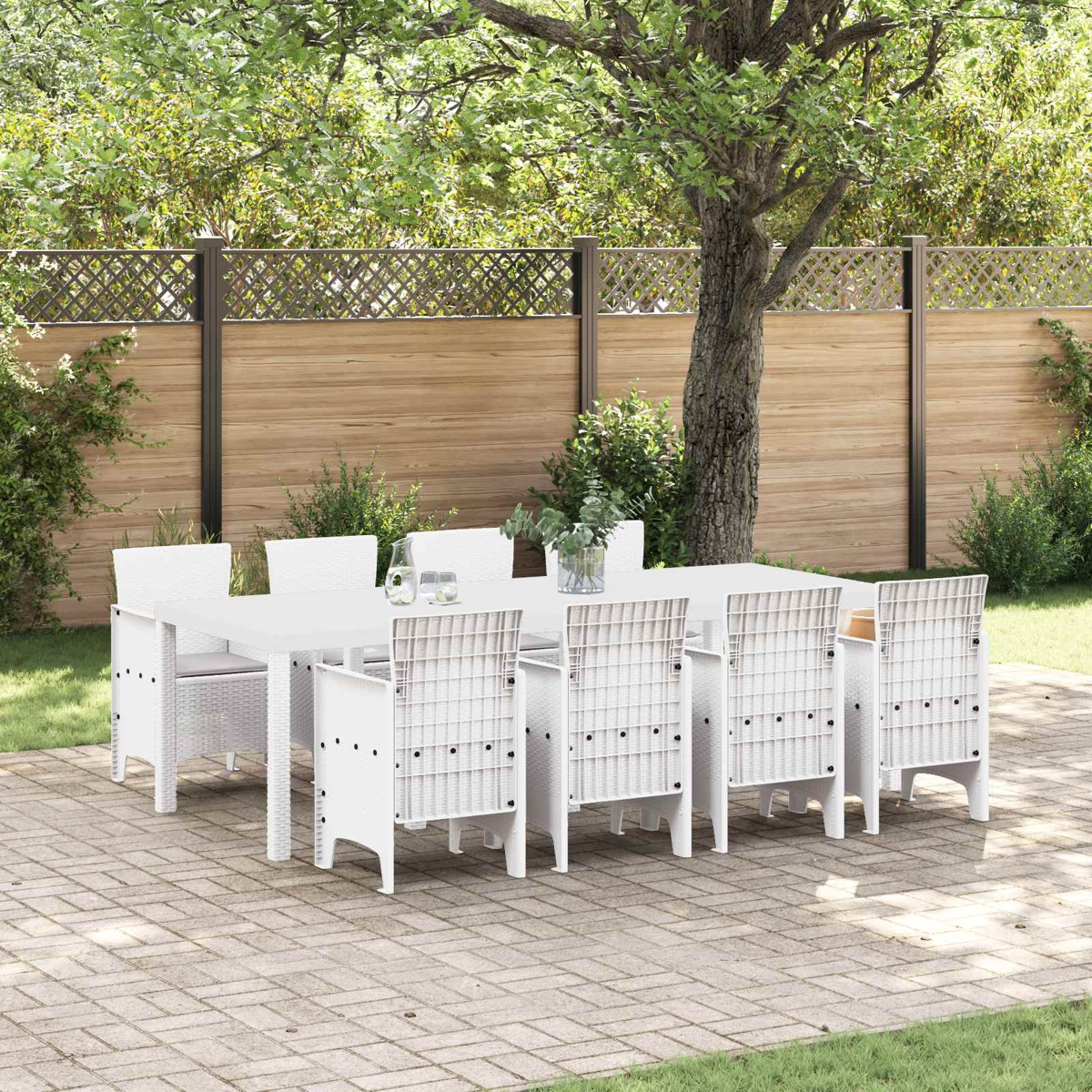 Ein weißes Esszimmer-Set mit Tisch und Stühlen auf einer gepflasterten Terrasse.