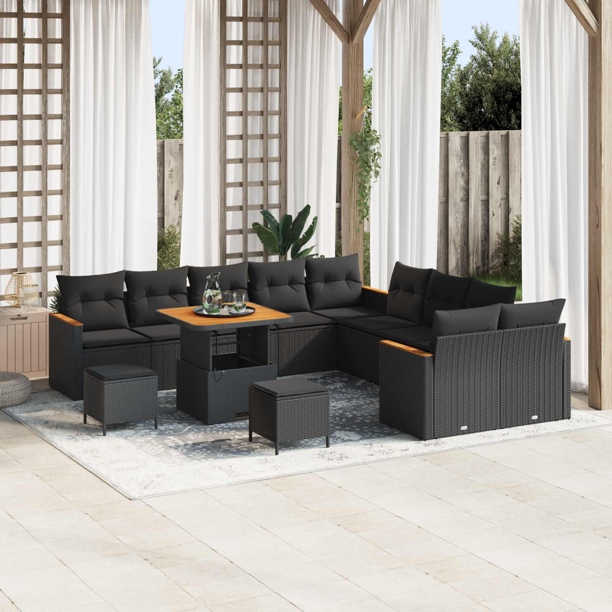 Salón exterior de mimbre negro, cojines, mesa y taburetes en un patio.