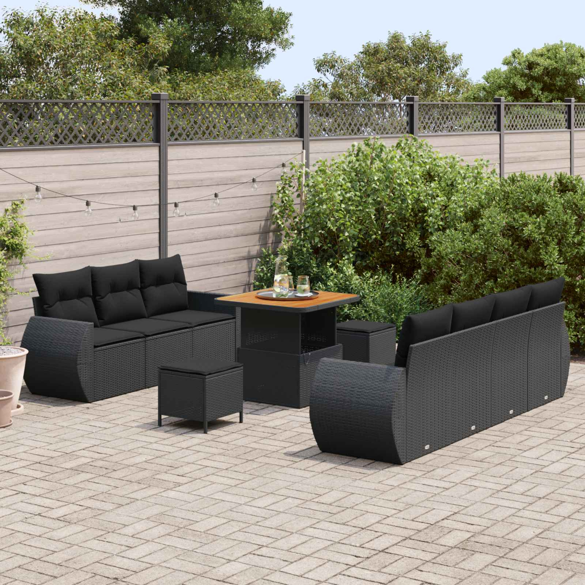 Dunkelgraue Rattan-Lounge-Möbel mit schwarzen Kissen auf einer Terrasse.
