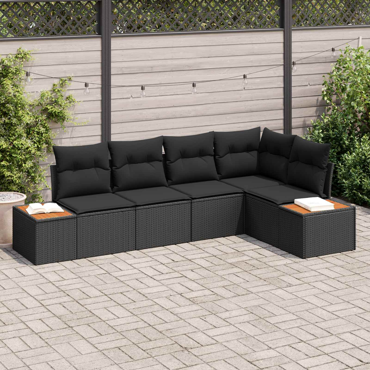 Dunkelgraue Lounge-Ecke mit Kissen auf einer gepflasterten Terrasse.