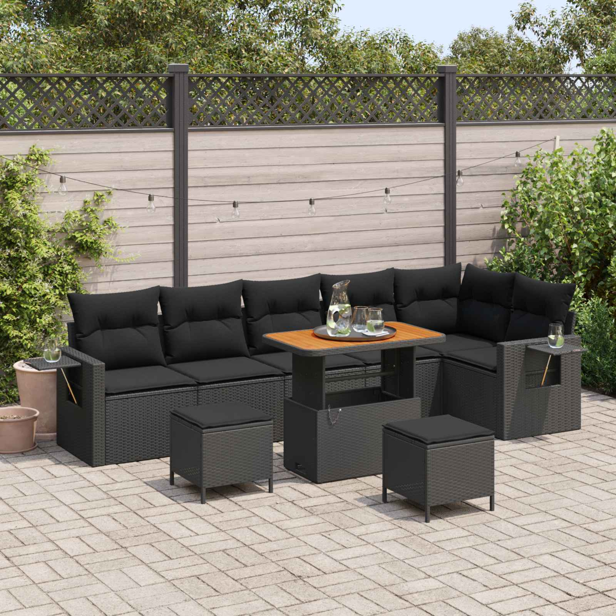 Ein dunkles Gartensofa mit Tisch und Hockern auf einer gepflasterten Terrasse.