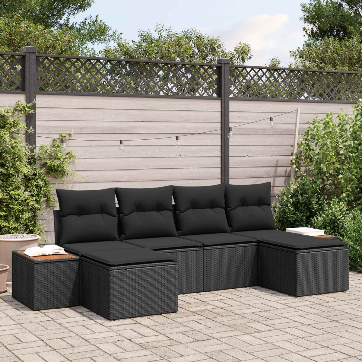 Schwarze Gartenmöbel aus Rattan mit Kissen auf einer Terrasse.