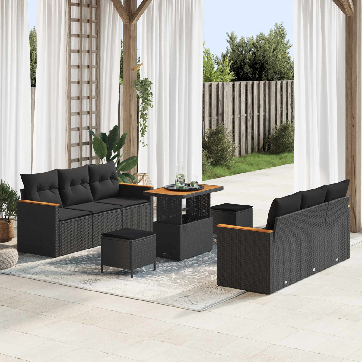 Ein schwarzes Rattansofa mit Holzakzenten steht auf einer Terrasse.