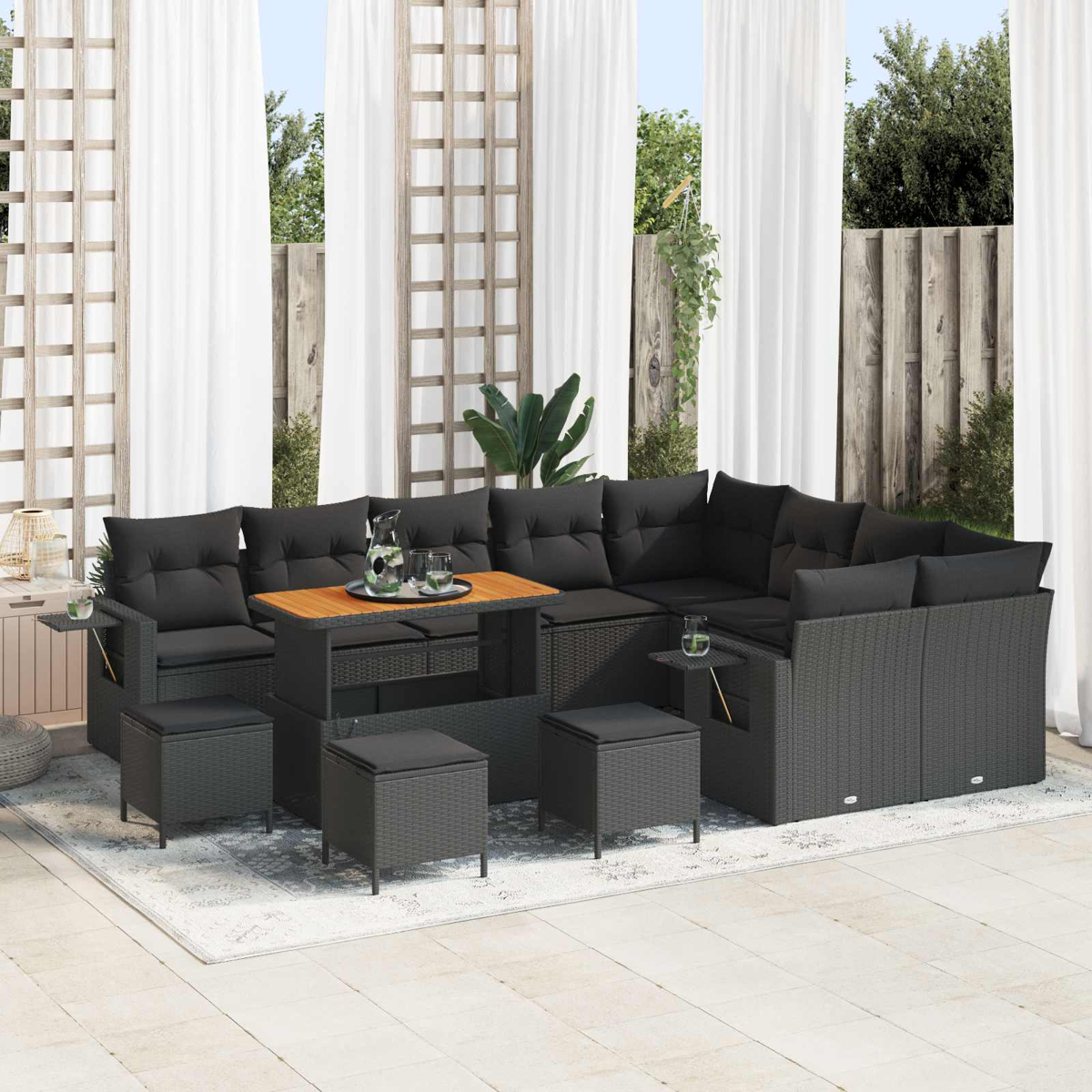 Dunkelgraue Outdoor-Lounge-Garnitur mit Tisch und Hockern auf Teppich.