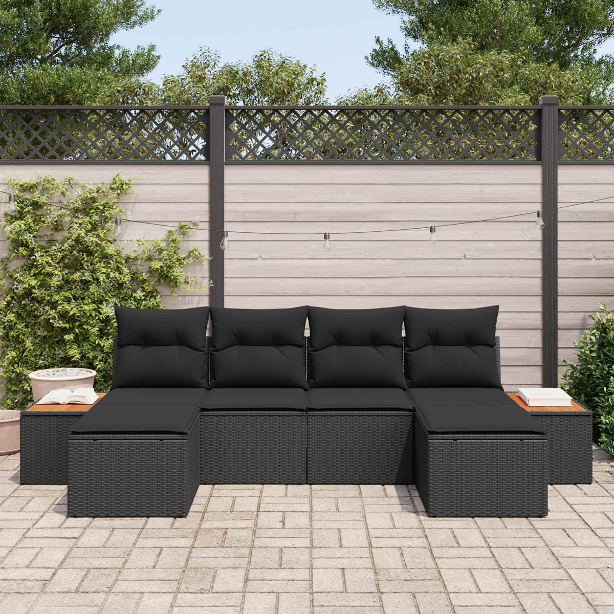 Dunkelgraues Rattan-Sofa mit schwarzen Kissen auf einer gepflasterten Terrasse.