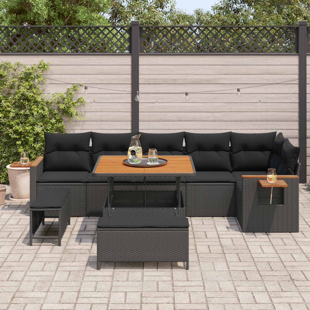 Dunkelgraue Lounge-Garnitur mit Tisch, Kissen und Lichtern im Freien.