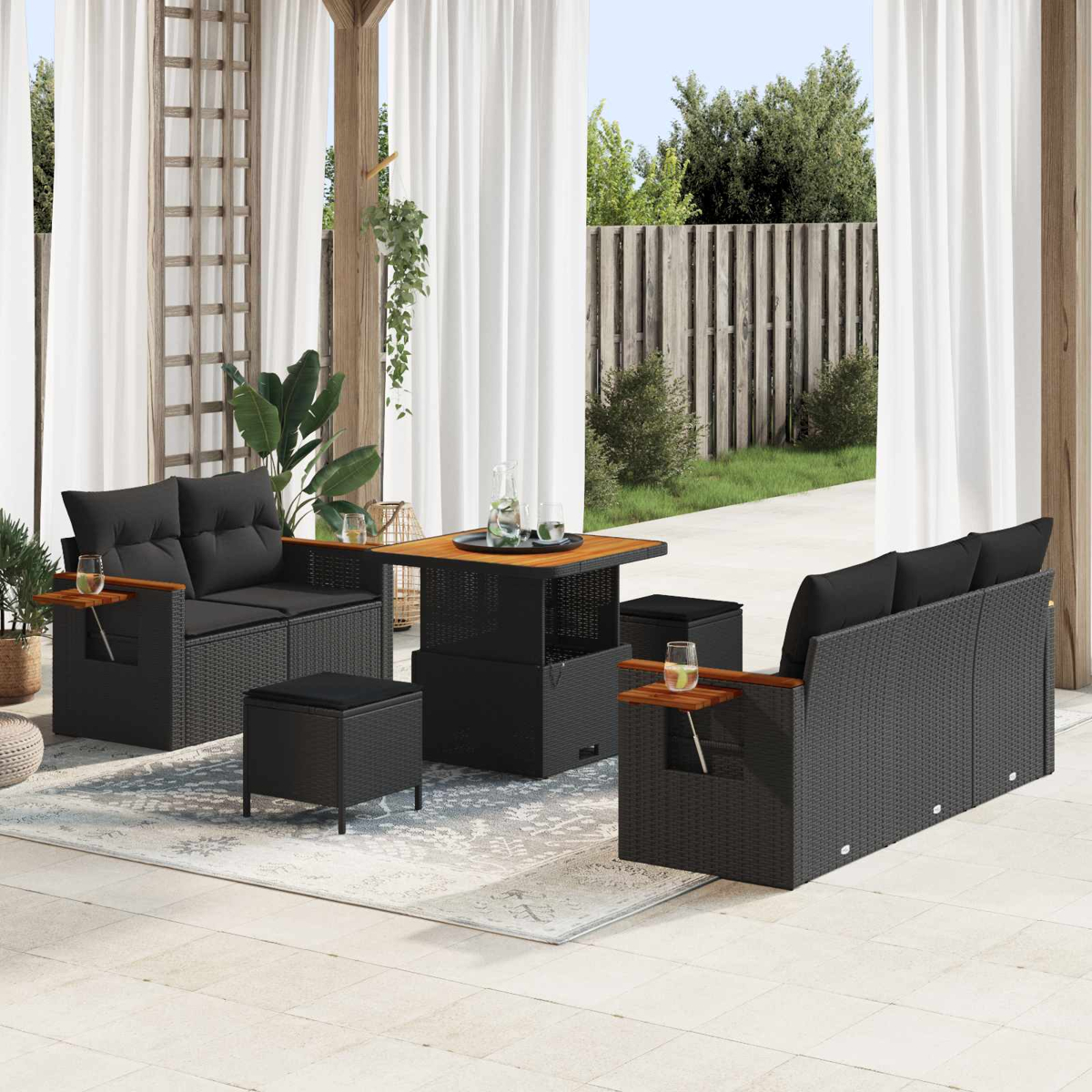 Dunkelgraue Rattan-Lounge-Möbel mit Holztisch, Hockern und Gläsern auf einer Veranda.