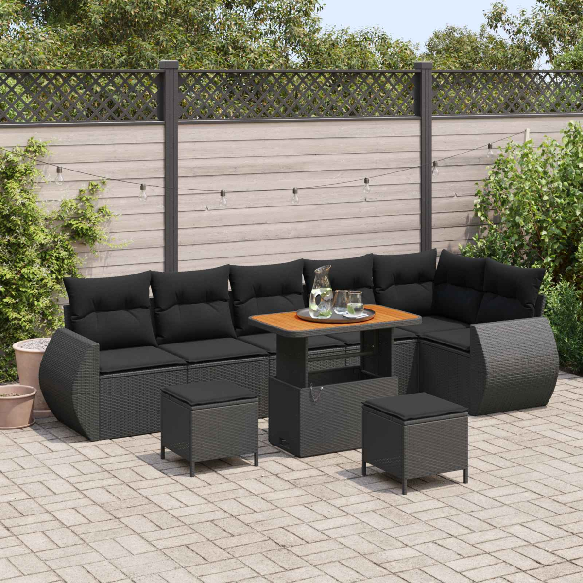 Dunkelgraue Rattan-Lounge-Möbel mit schwarzen Kissen und einem höhenverstellbaren Tisch.