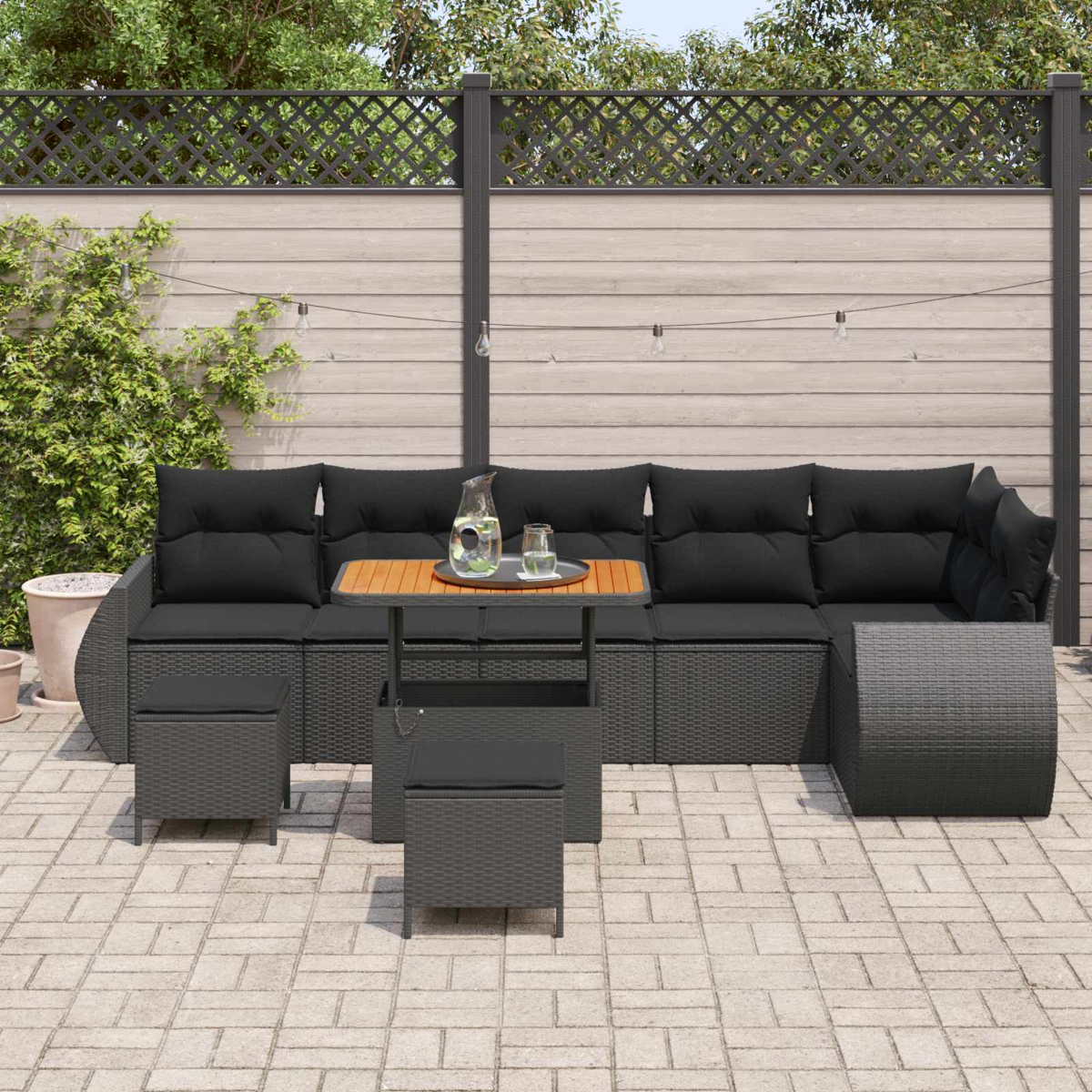 Dunkelgraue Lounge-Möbel mit schwarzen Kissen auf einer gepflasterten Terrasse.