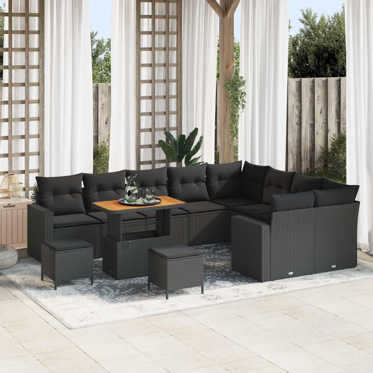 Un sofá de ratán oscuro con cojines negros y una mesa de madera en un patio.