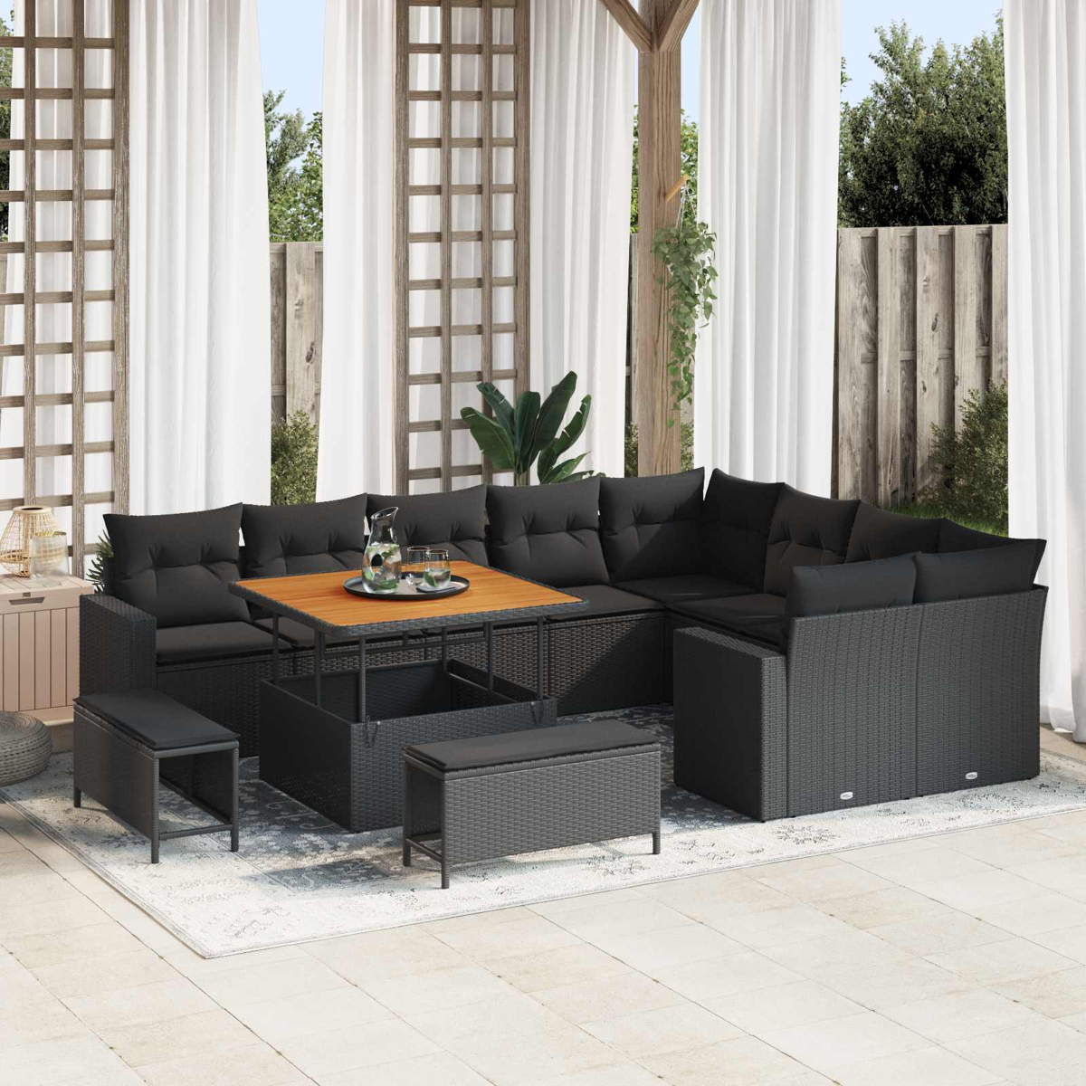 Ein dunkles Rattan-Lounge-Set mit Kissen und Holztisch auf einer Terrasse.