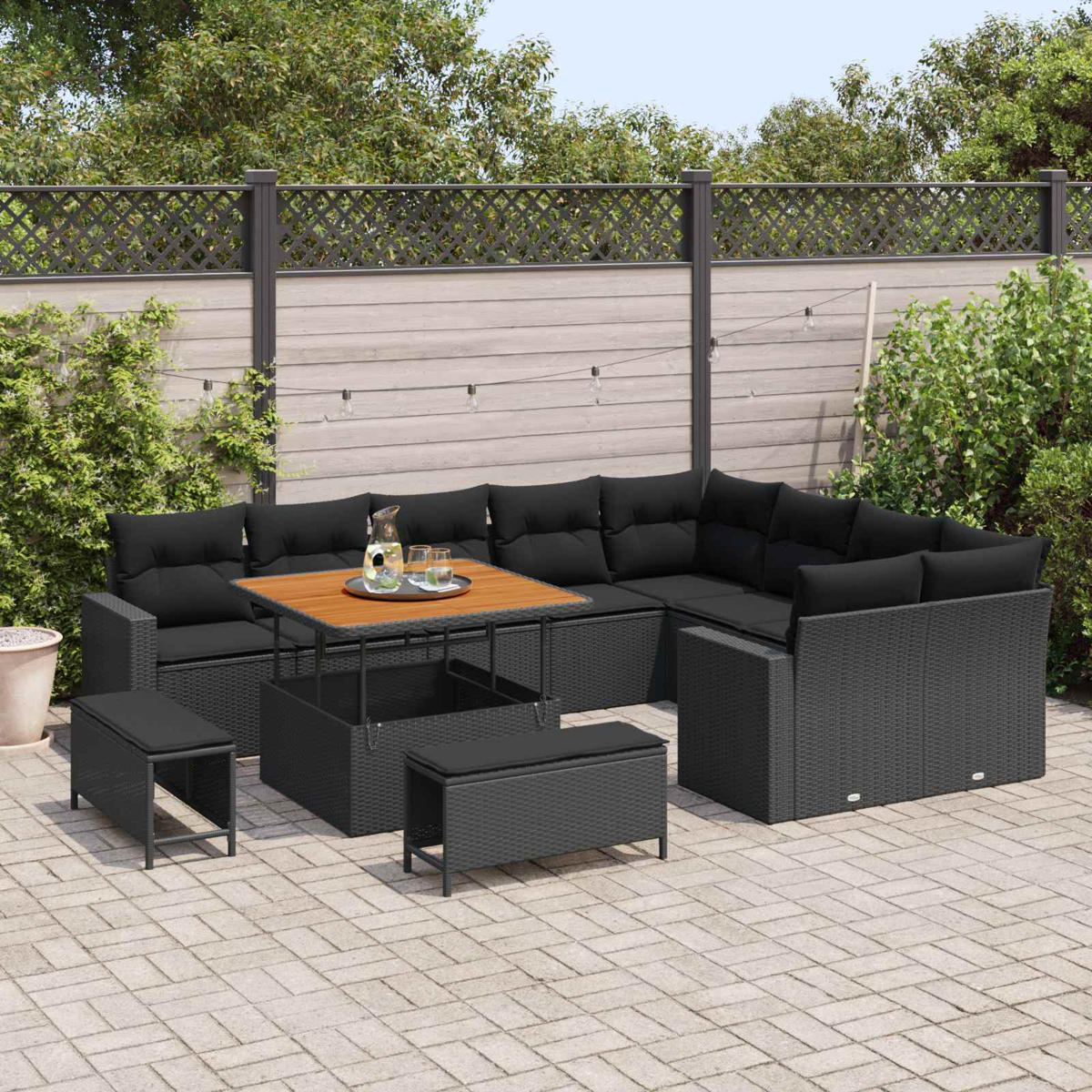 Ein dunkles Rattansofa mit schwarzem Polster und einem Holztisch im Freien.