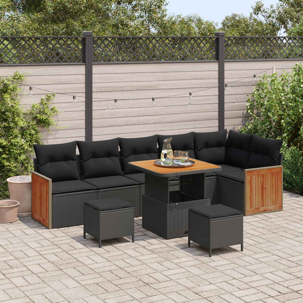 Un conjunto de salón exterior oscuro con cojines y mesa en un patio pavimentado.
