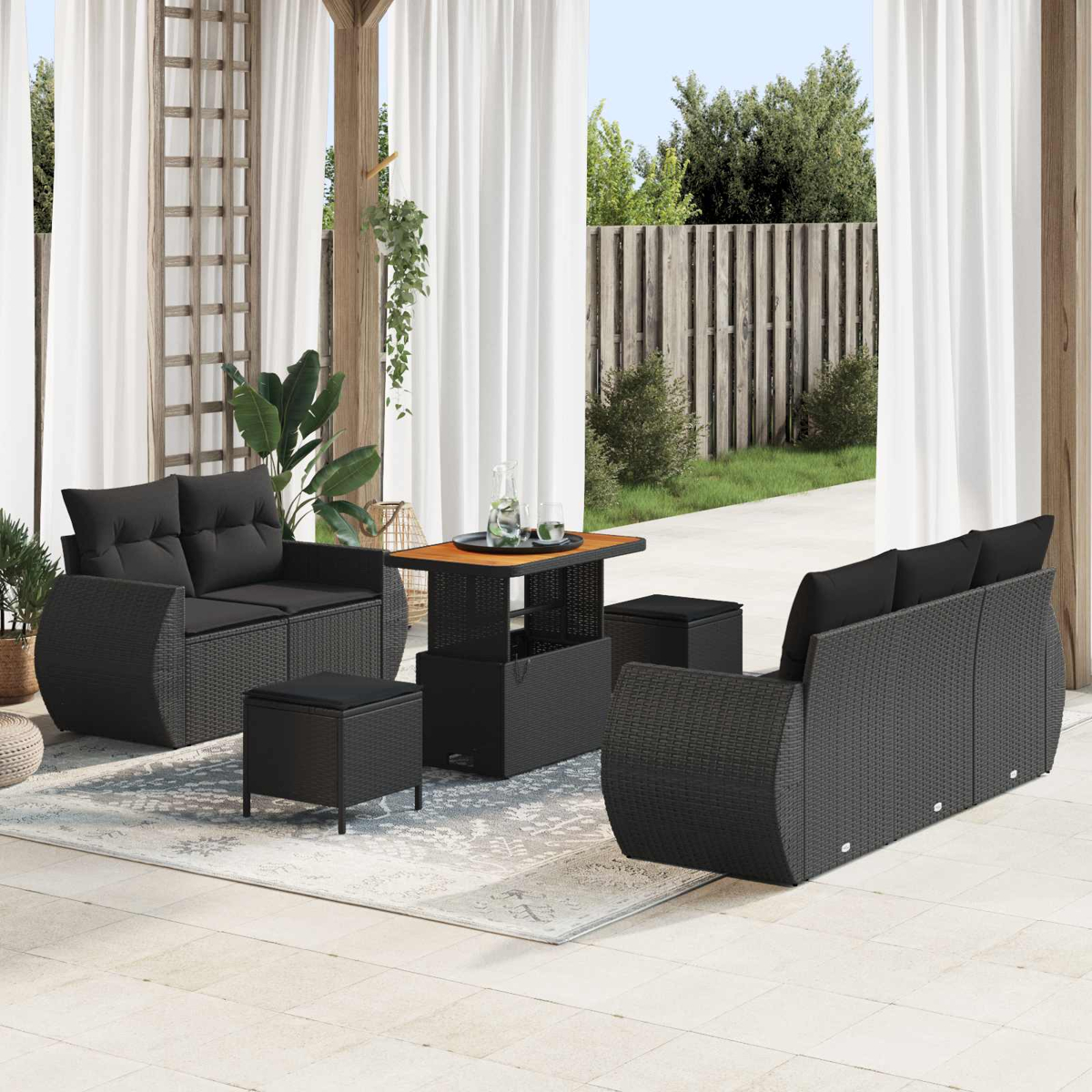 Schwarzes Rattan-Gartenmöbelset mit Sofa, Sesseln und Tisch auf einer Terrasse.