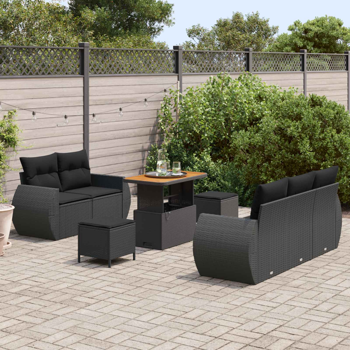 Dunkle Rattansitzgruppe mit Kissen auf einer gepflasterten Terrasse.