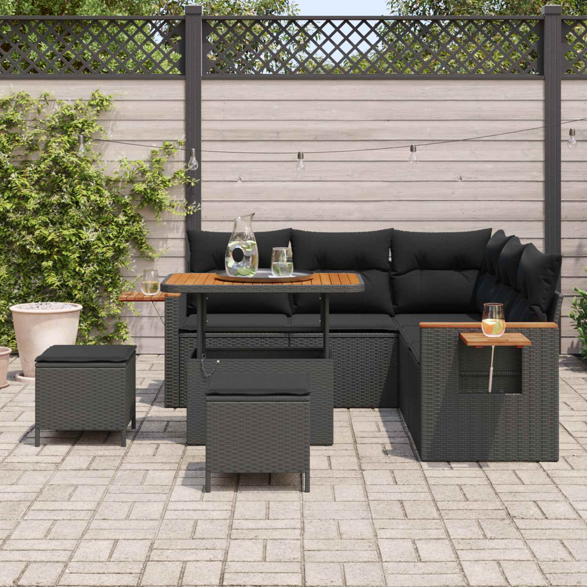 Dunkelgraue Lounge-Garnitur mit schwarzem Kissen auf einer gepflasterten Terrasse.