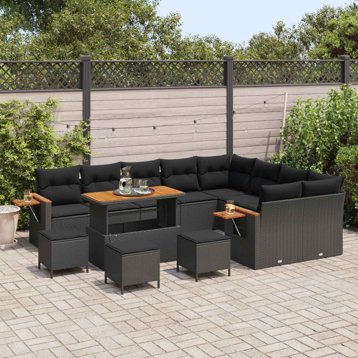 Dunkelgraues Lounge-Set mit schwarzen Kissen und Holz-Couchtisch auf einer gepflasterten Terrasse.