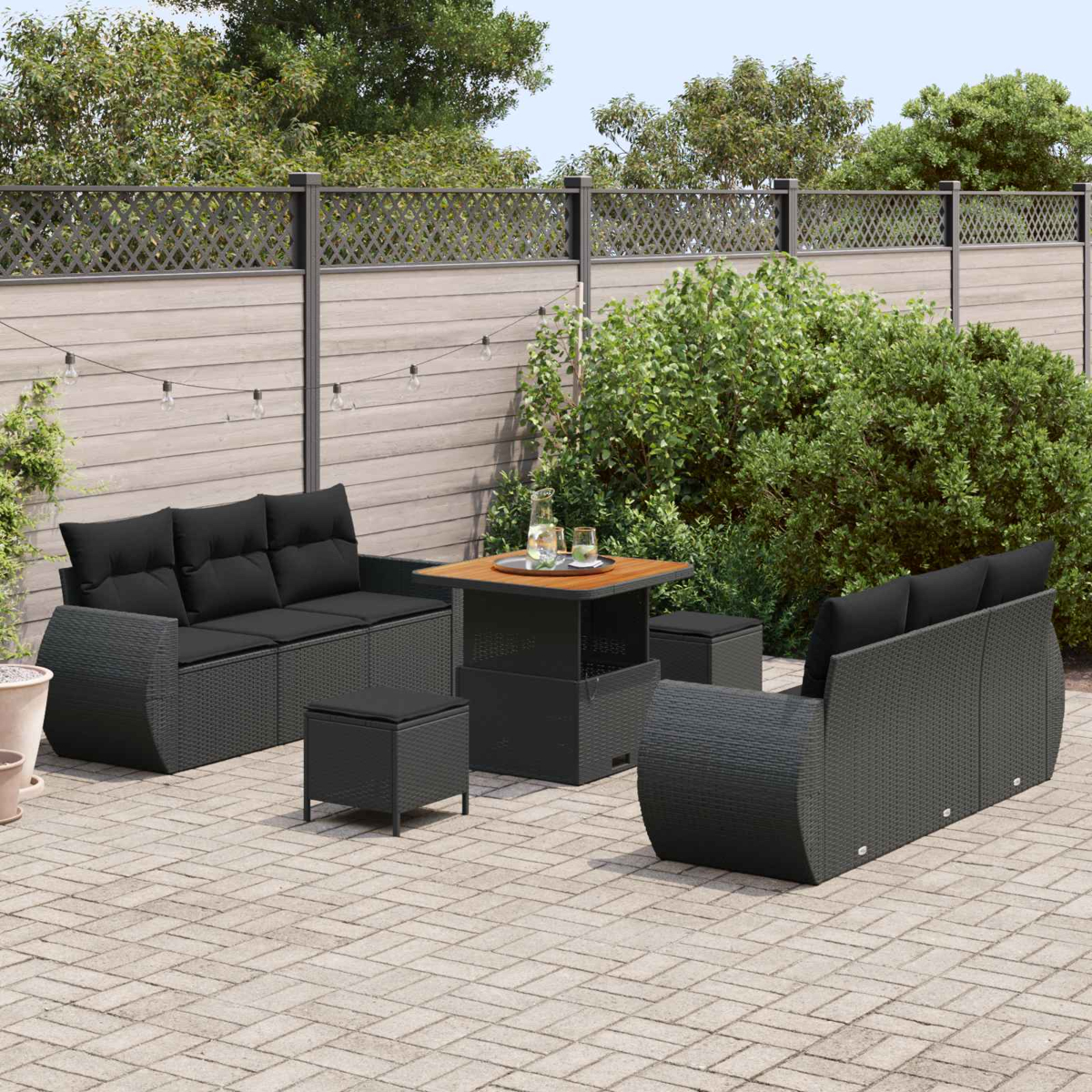 Draußenmöbel-Set mit schwarzem Sofa, Hockern und Tisch auf einer Steinterrasse.