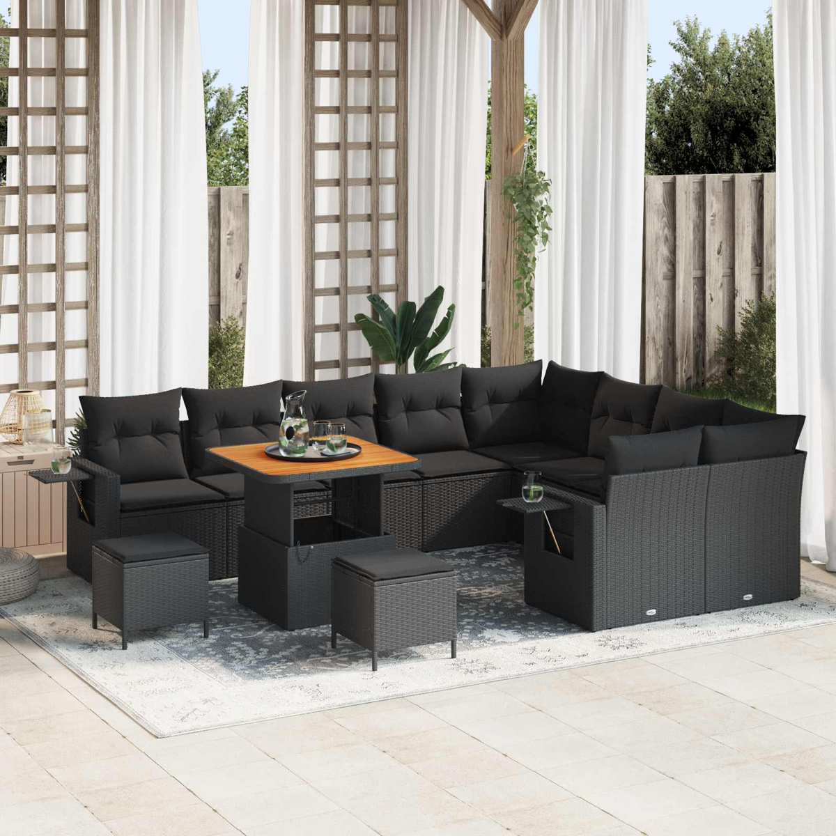 Dunkelgraue Lounge-Garnitur mit Tisch, Hockern und Kissen auf einer Terrassenfliese.