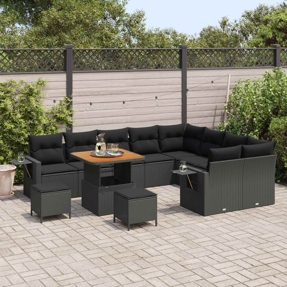 Graues Rattan-Ecksofa mit schwarzen Kissen und einem Tisch im Freien.