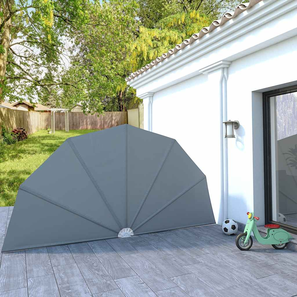Ein graues Sonnensegel steht auf einer Holzterrasse neben einem Haus mit einem Spielzeugroller.