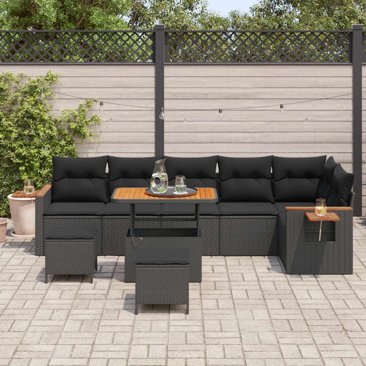 Dunkelgraue Lounge-Möbel mit schwarzen Kissen auf einer gepflasterten Terrasse.