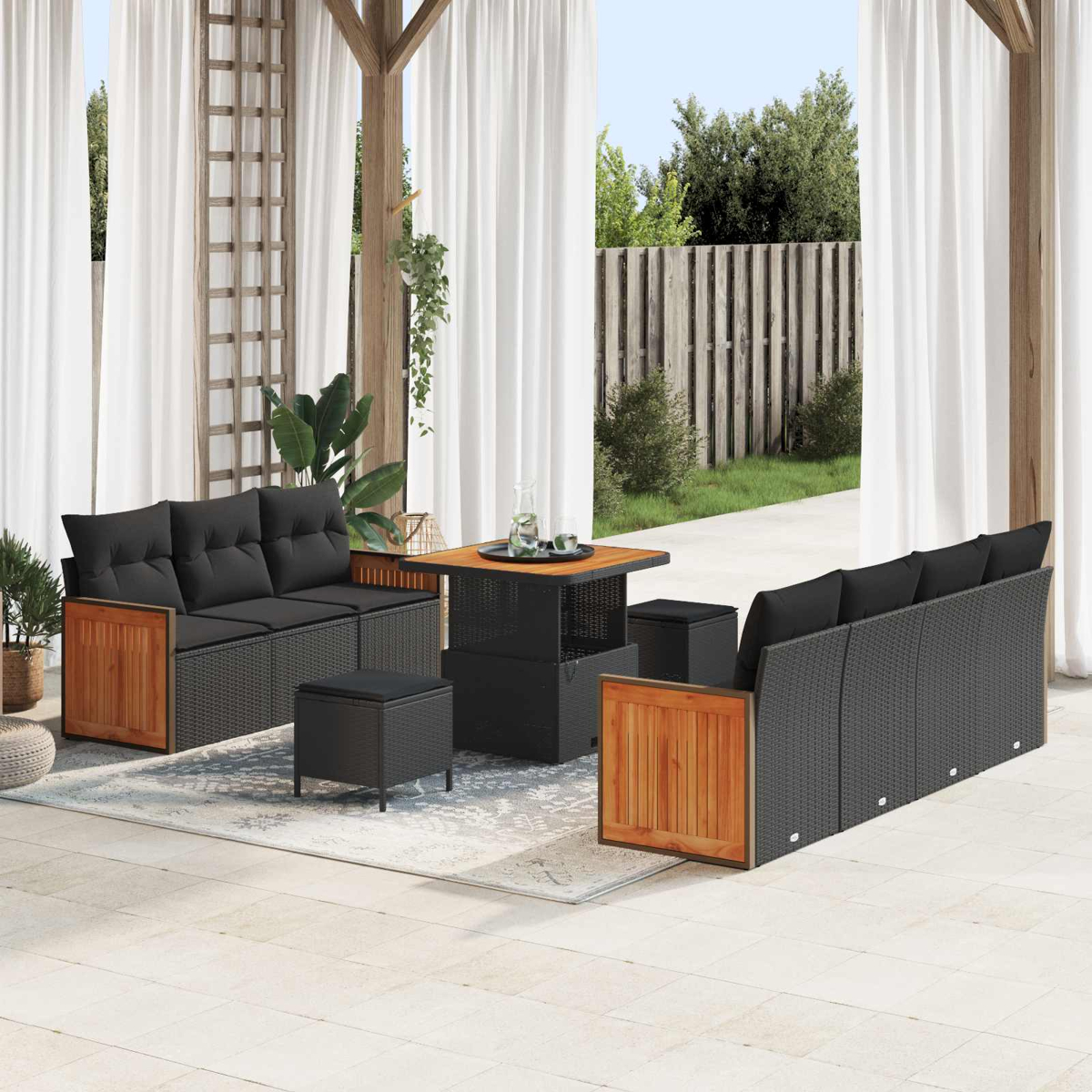 Ein Gartenmöbelset mit schwarzen Kissen und Holzdetails auf einer Terrasse.