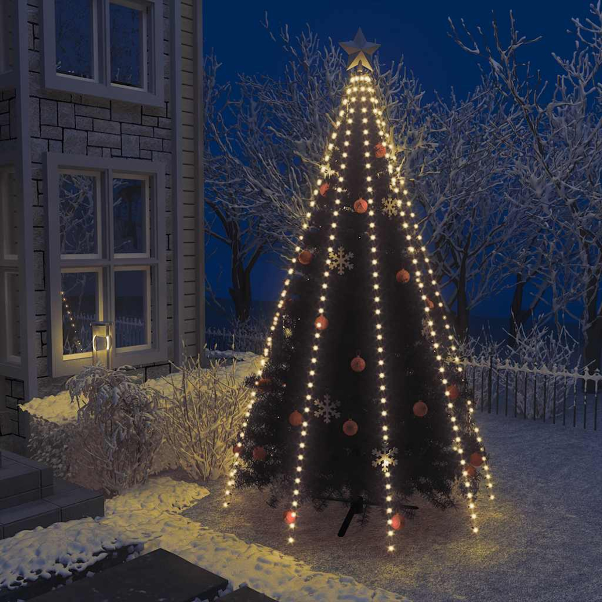 Ein geschmückter Weihnachtsbaum mit Lichtern und Kugeln im Schnee vor einem Haus.