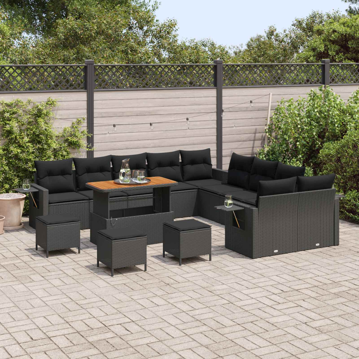 Dunkelgraues Loungeset mit schwarzen Kissen auf einer Pflastersteinveranda.